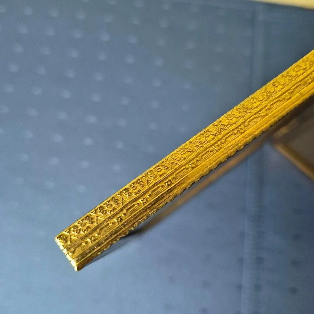 Vintage hinged gold picture frame with vertical ridges.